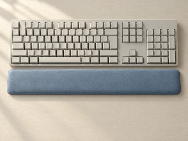 A generic full-size keyboard and separate blue palm rest on an uncluttered desk.